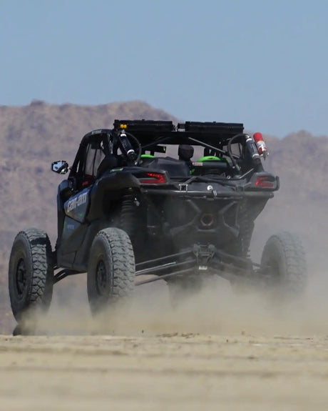A dark-colored off-road utility vehicle kicking up dust.